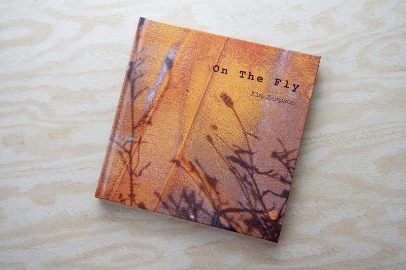 Hardcover book with orange and purple gradient cover featuring silhouetted plant stems against warm sunset tones.