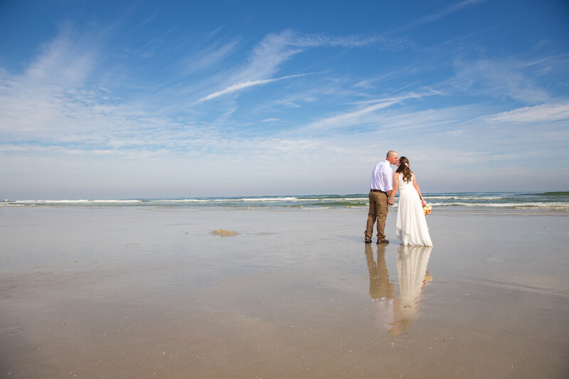A couple kissing on the beach captured by beach wedding photographers using a wider lens