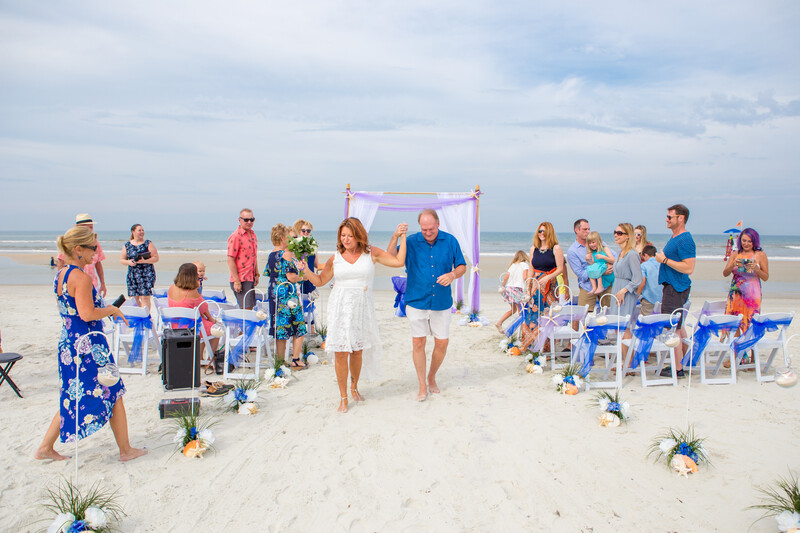 beach wedding photography that shows a couple walking down the aisle after their first kiss