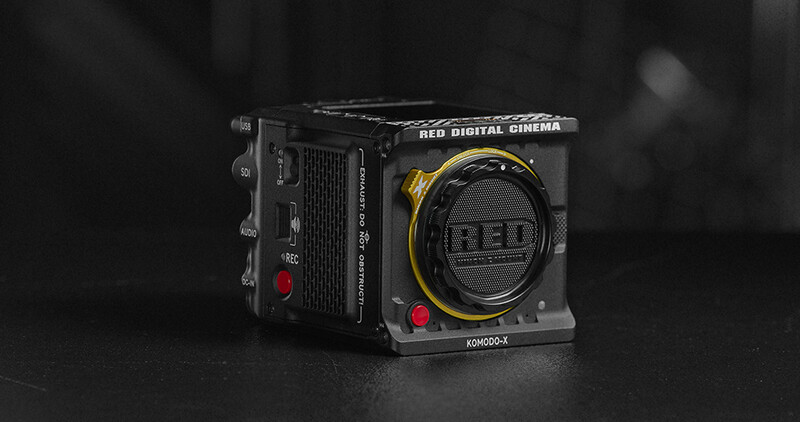 RED Digital Cinema camera body with lens mount and red control buttons against dark background.