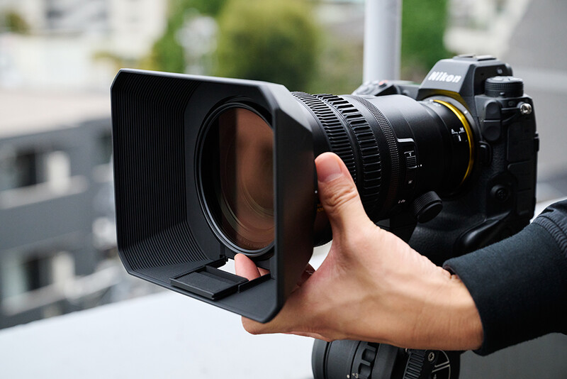 Cinematographer holding a cinema camera with a rectangular matte box attached to the front.