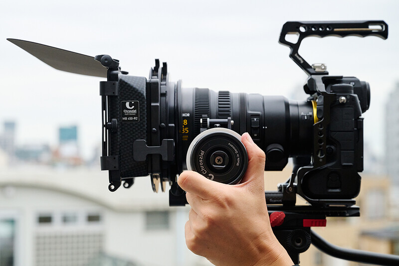 Filmmaker holding a cinema camera rig with matte box and follow focus mounted on rooftop location.