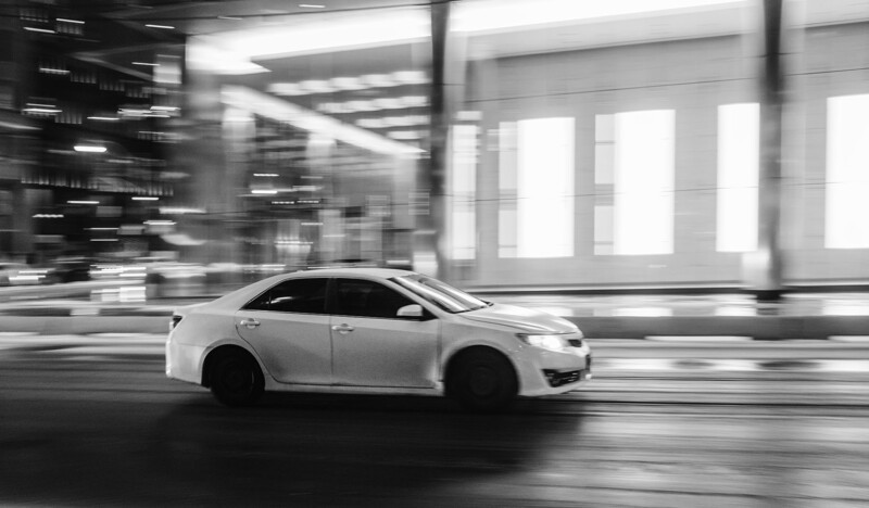 White sedan moving through a parking garage with motion blur applied to surroundings.