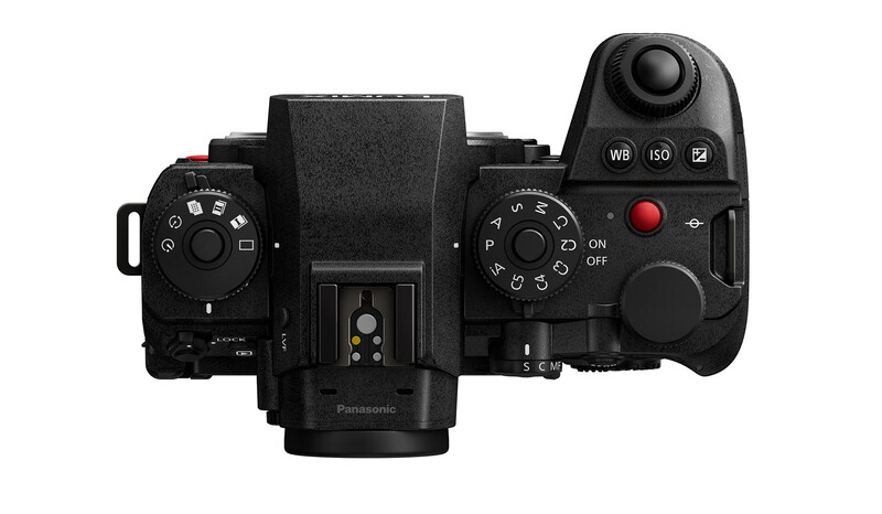 Top-down view of a mirrorless camera with dual control dials, joystick, and red record button.