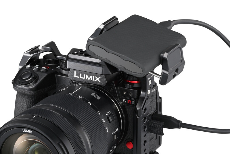 Panasonic Lumix S1R mirrorless camera with external recorder mounted on top via cable.