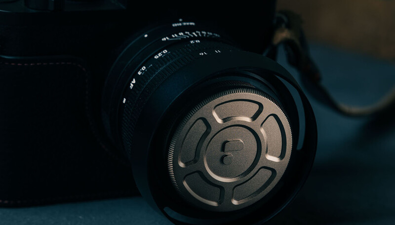Close-up of a vintage camera lens with aperture blades and depth-of-field markings visible against a blue background.
