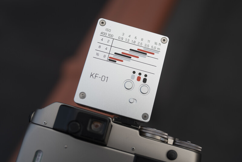 White KF-01 color checker card being held against a person's clothing in natural light.