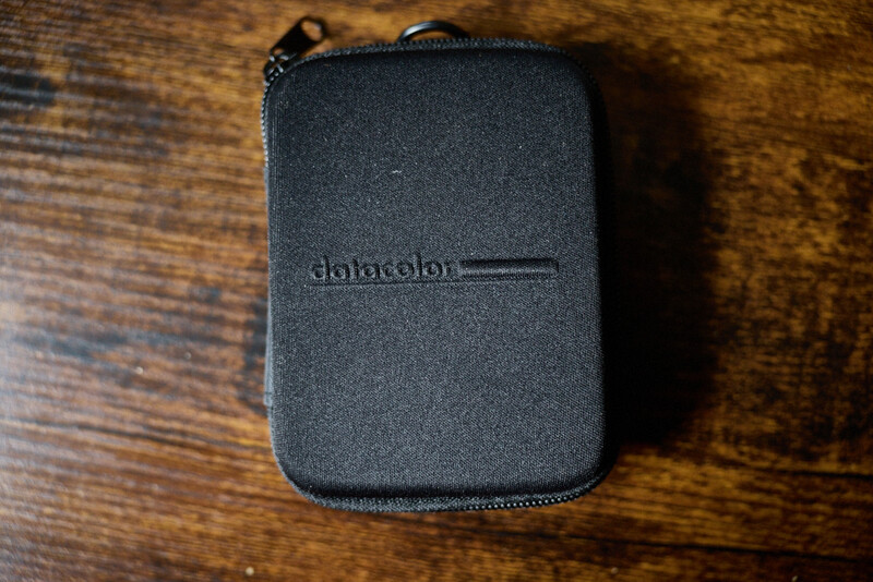 Black zippered pouch with debossed text on wooden surface.