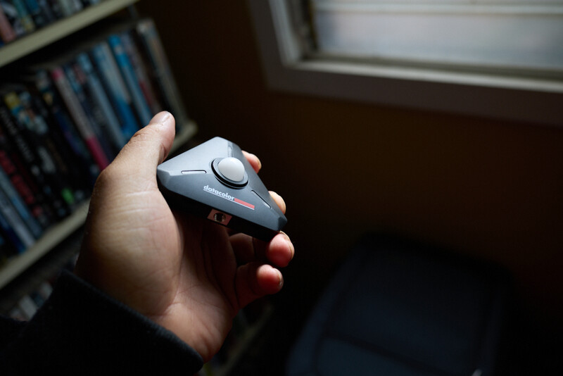 Hand holding a gaming controller with thumbstick and buttons visible indoors.