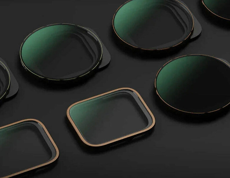 Optical camera filters with dark green glass and metal frames arranged on gray background.