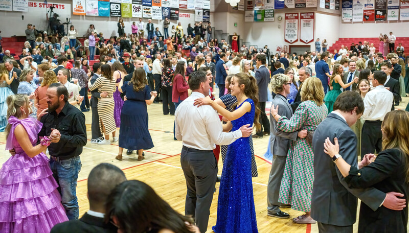 Large crowd of formally dressed people dancing and socializing in a gymnasium during an indoor event.