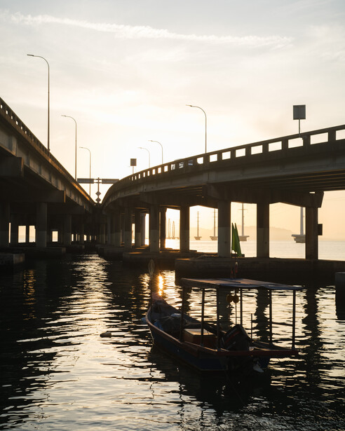 Concrete highway overpass spanning calm water at dusk with warm golden light reflecting off the surface.