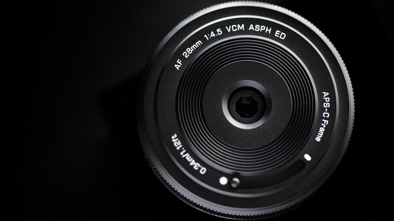 Close-up of a 28mm f/1.4 prime lens with VCM autofocus and ED glass elements, showing the front element and engraved specifications.