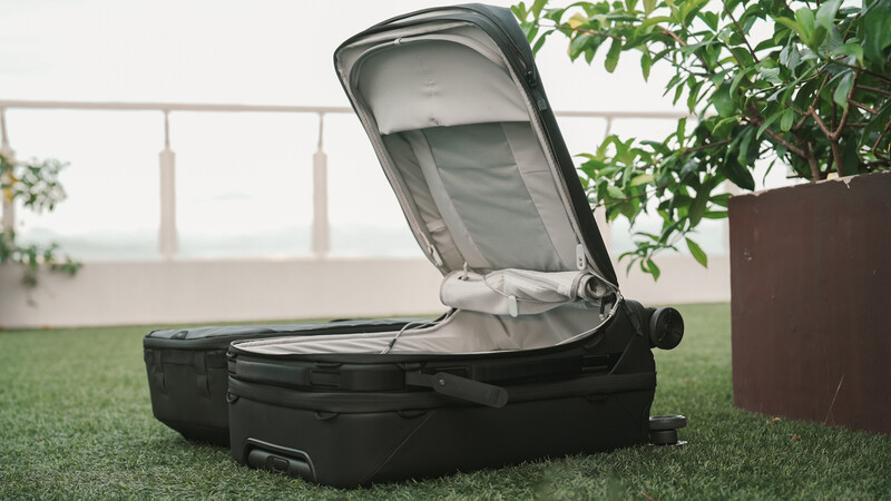 Open black rolling suitcase with gray interior displayed on grass indoors.