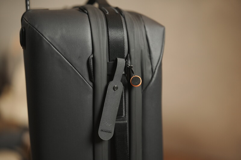 Close-up of a black camera bag's top compartment with dual carrying straps and gold-toned hardware.