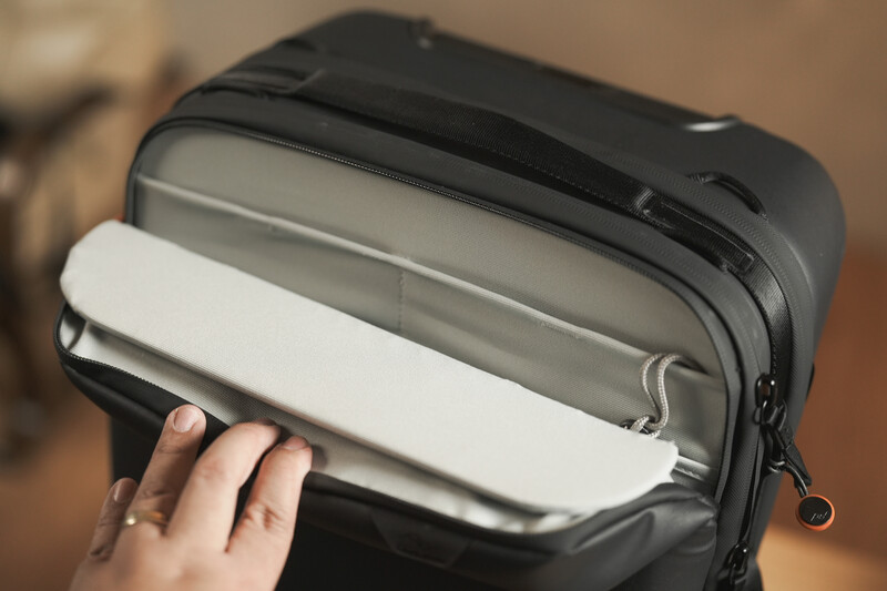 Person's hand opening a gray camera bag or protective case with white padded interior compartment.