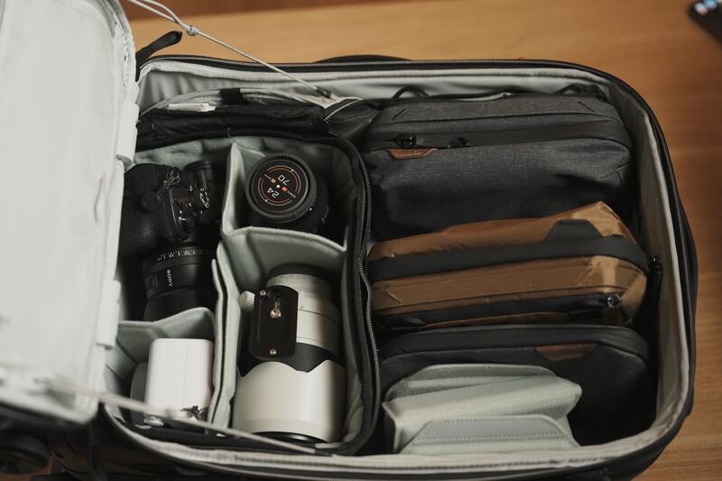 Organized camera gear packed in a travel case with compartments holding lenses, camera body, and accessories.