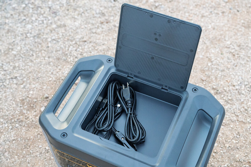 Open gray plastic case displaying coiled black cables inside compartments.