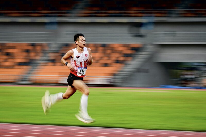 Male runner sprinting on an indoor track with motion blur creating a sense of speed and momentum.