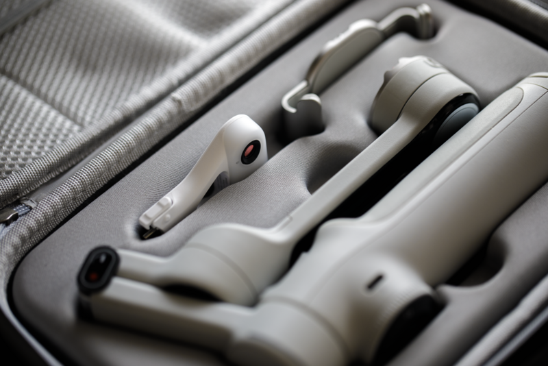 White wireless earbuds and charging case arranged in a gray protective carrying case with fabric lining.