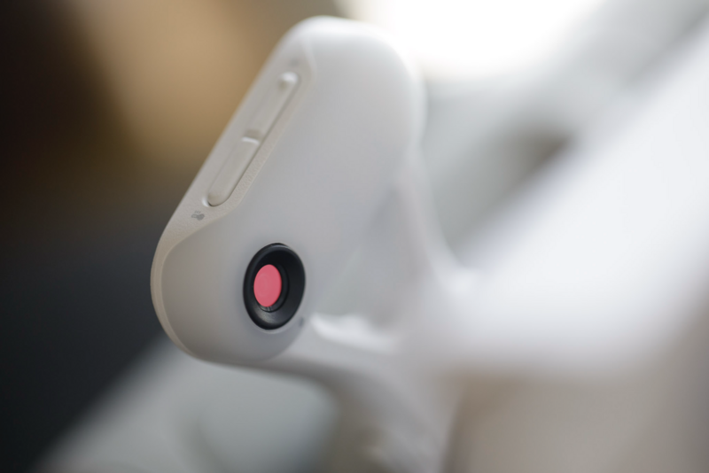 Close-up of a white robotic head with a red circular lens or eye detail in sharp focus.
