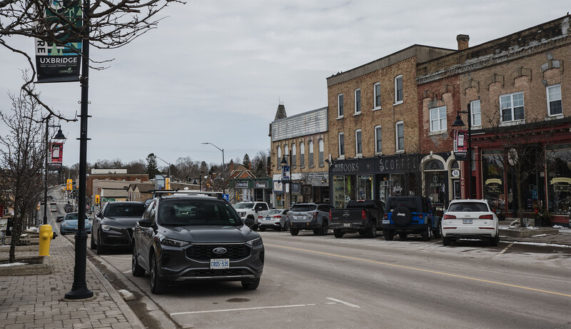 Main street lined with parked cars, historic brick buildings, and overcast sky.