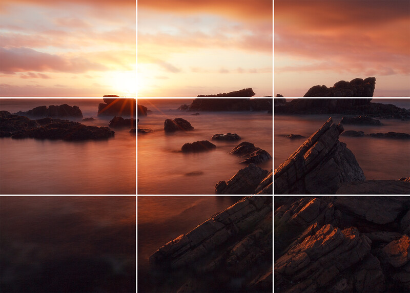 Rocky coastline at sunset with golden light reflecting off wet rocks and calm water, divided by rule-of-thirds grid lines.