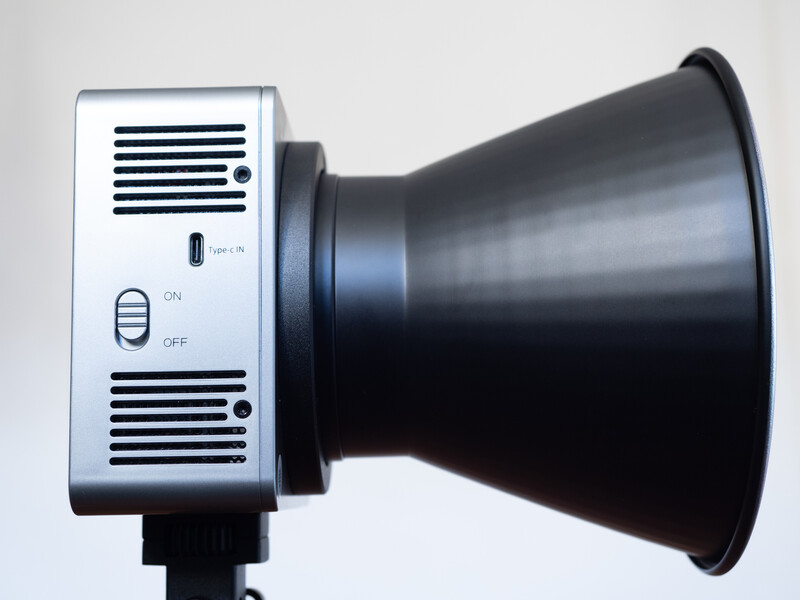Compact studio light with white control panel and black reflector cone attachment.