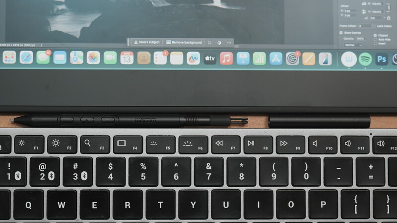 MacBook Pro keyboard and trackpad with editing software visible on display above.