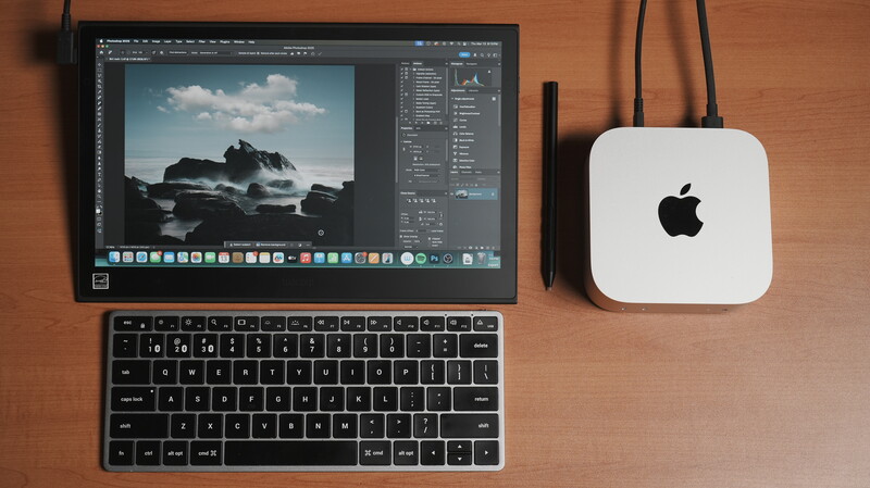 Mac mini beside external display running Lightroom with coastal landscape photograph open.