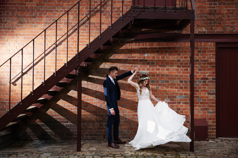Bride and groom dance under the stairs in an alley.