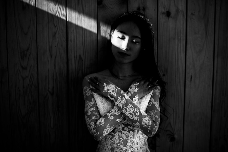 Bride stands in dark room with just a strip of light across her eyes.