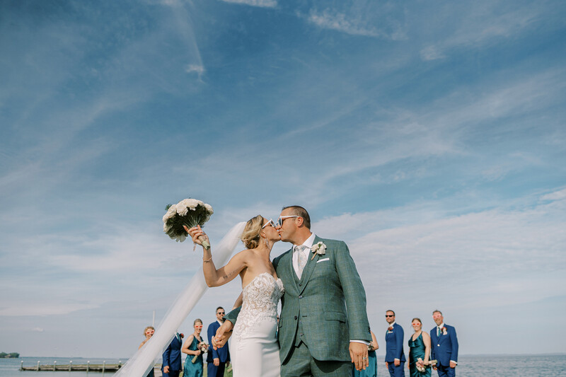 Newlyweds kiss in front of the bridal party.