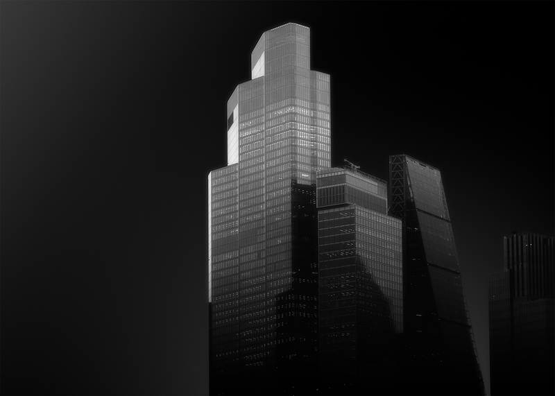 Modernist skyscrapers photographed from below against a dark sky, emphasizing geometric forms and vertical lines.