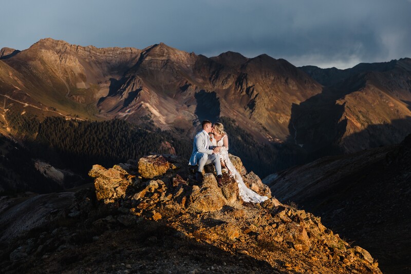 Bride and groom kiss on rocks during golden hour for hard light photography tips