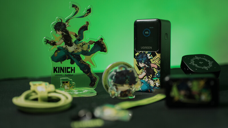 Collection of gaming merchandise arranged on dark surface against green backdrop, including character figure, device, and accessories.