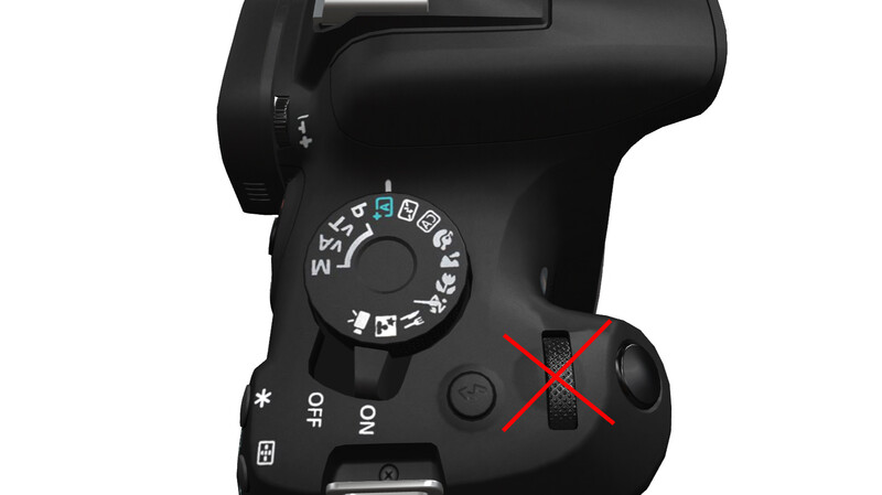 Top-down view of a DSLR camera with mode dial and controls highlighted with a red X mark.