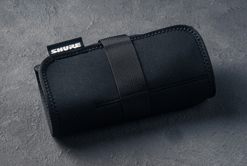 Black neoprene microphone carrying case with shoulder strap and Shure branding label.