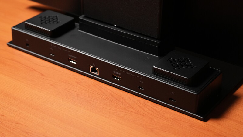 Black media device with Ethernet and USB ports positioned on an orange wood surface beneath a display monitor.