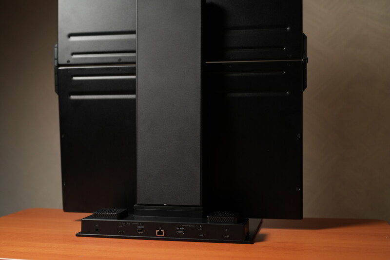 Black computer tower and networking equipment on wooden surface against neutral background.
