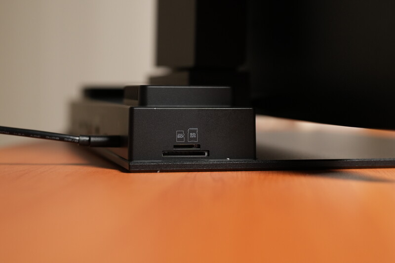 Black charging dock with dual card slots positioned on orange desk surface with cables.
