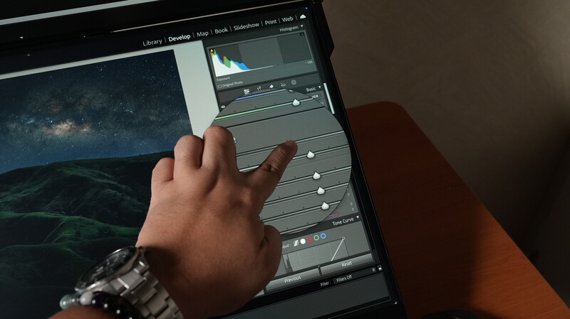 Photographer's hand adjusting sliders in Lightroom while editing an astrophotography image of the Milky Way.