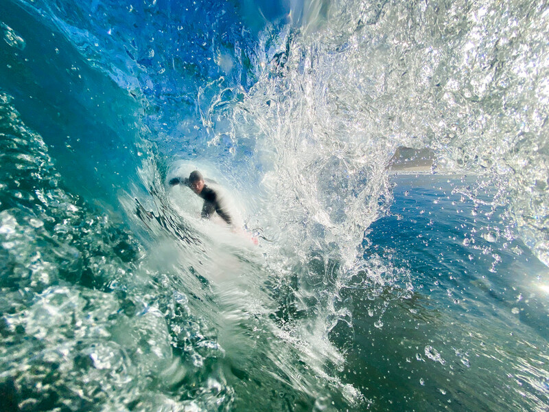 Surfer riding a wave captured from underwater perspective with shallow depth of field.