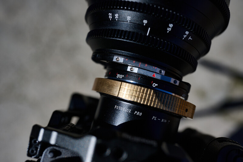 Vintage cinema lens with brass focus ring mounted on camera body in close-up detail.