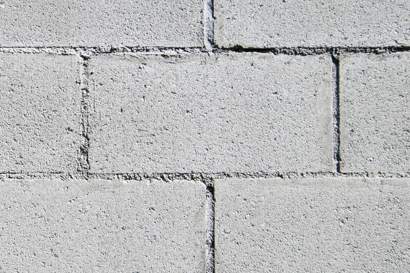 Close-up of concrete block wall showing horizontal mortar joints and vertical seams between light gray blocks.