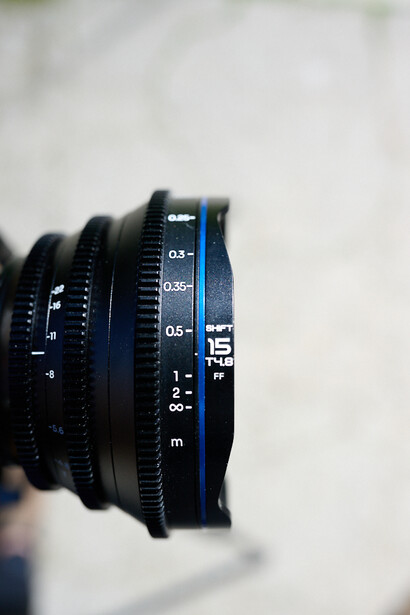 Close-up of cinema lens barrel showing focus and aperture markings with soft-focus background.