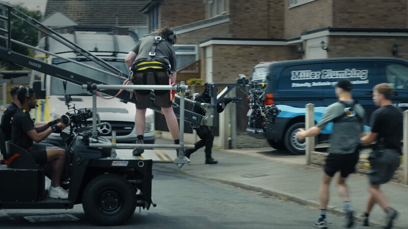 Film crew operating camera equipment on a stabilized rig while capturing an athlete on a platform during an urban outdoor shoot.