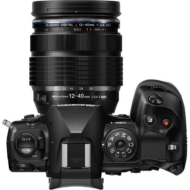 Top-down view of a mirrorless camera with 12-40mm lens attached and remote control beside it.