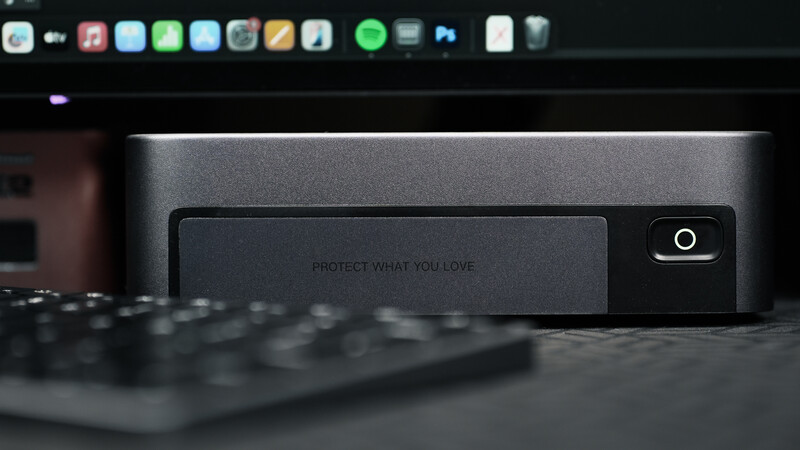 Dark desktop workspace with monitor, keyboard, and external storage device displaying motivational text.