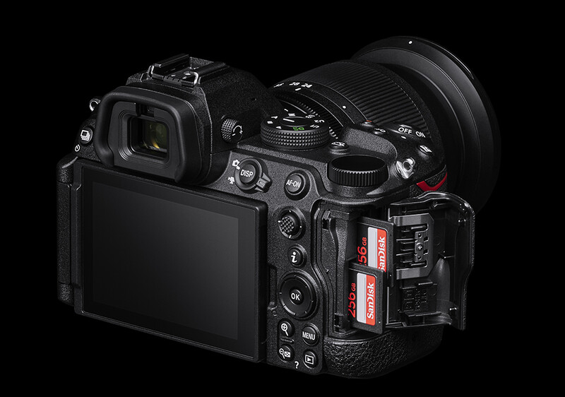Professional mirrorless camera with large telephoto lens and dual memory card slots visible on the right side.